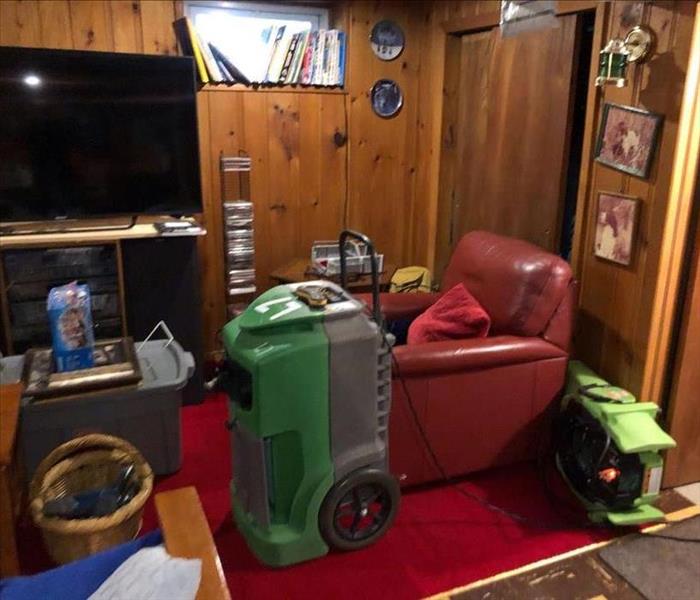 Red chair in a basement with SERVPRO drying equipment