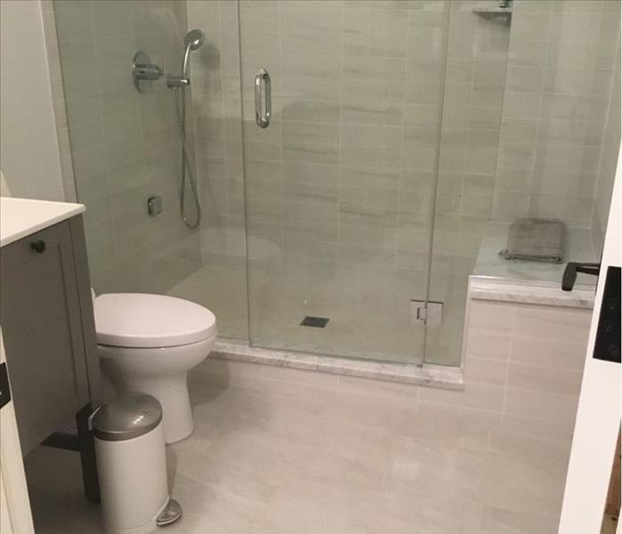 Clean bathroom with white tile floor and shower stall