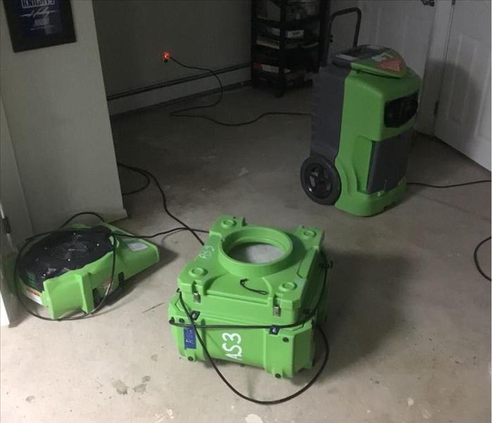 Laundry room with bare floor and SERVPRO drying equipment