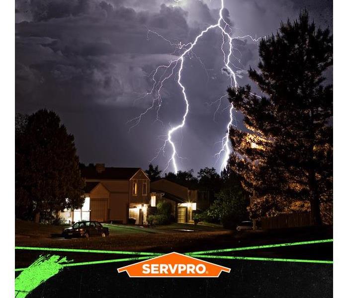 Lighting in the sky over a neighborhood with the SERVPRO logo.